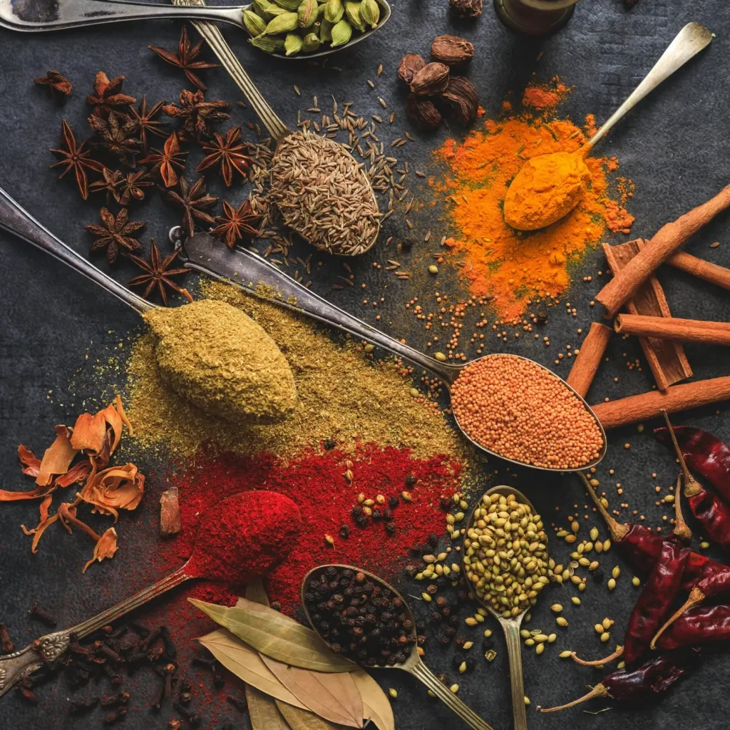 Vibrant array of spices including turmeric, cumin, and chili arranged on a dark surface.